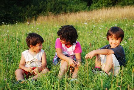 Happy little children in grass on meadowの写真素材