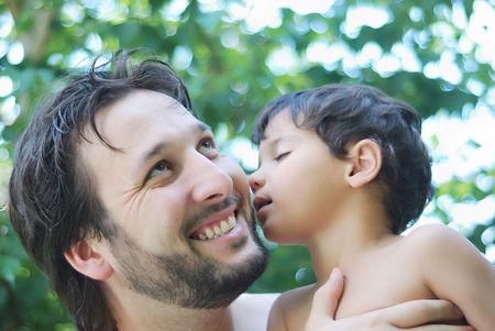 Lovely boy and his father holding him in hands in natureの写真素材