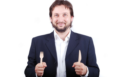A young male holding fork and spoon in hands
