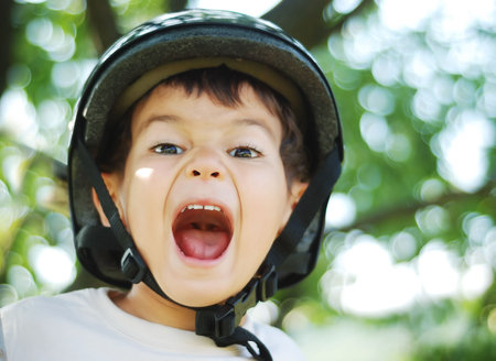 Little very cute kid with helmet on head and opened mouthの写真素材