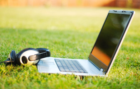 A laptop and headset on green meadow
