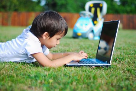 Cute kid is laying on laptop in beautiful environmentの写真素材