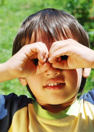 Little boy is looking trough his hands as binocularsの写真素材