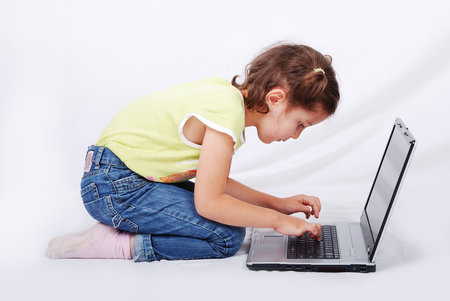 Cute little girl is playing and learning on laptop