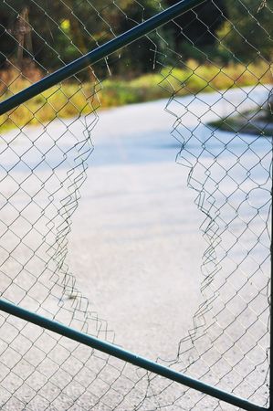 Hole made in wire fenceの写真素材