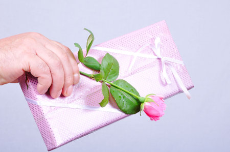 Gift and pink rose in male hand