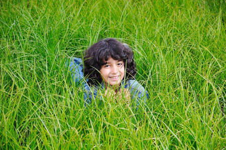 A little cute happy girl laying on green groundの写真素材