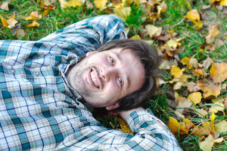 Happy positive young man on fall groundの写真素材