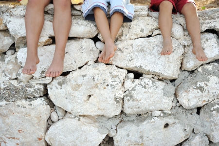 Children sitting on wall, happy boys laughingの写真素材