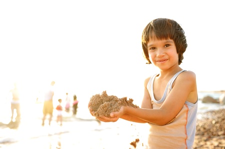 Kid on beach in sand playing, people around, summer hot nice timeの写真素材