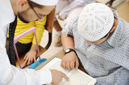 Education activities in classroom at school, Muslim teacher showing Koran to kidの写真素材
