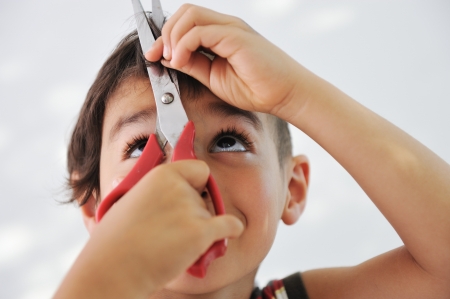 Kid cutting hair to himself with scissors, funny lookの写真素材