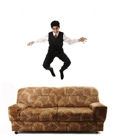 Young businessman jumping high on sofa, isolated, conceptual ideaの写真素材