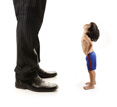 Little small child  is looking at the giant legs of  businessman adultの写真素材