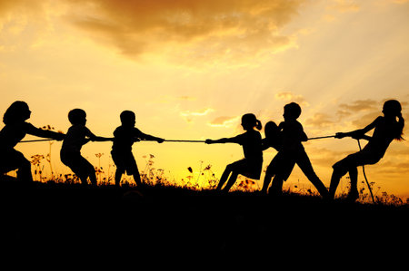 Silhouette, group of happy children playing on meadow, sunset, summertimeの写真素材