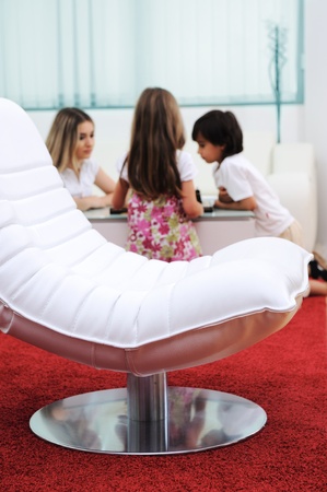Modern furniture in home, white leather chair, family in backgroundの写真素材