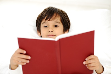 Kid reading book in bedの写真素材