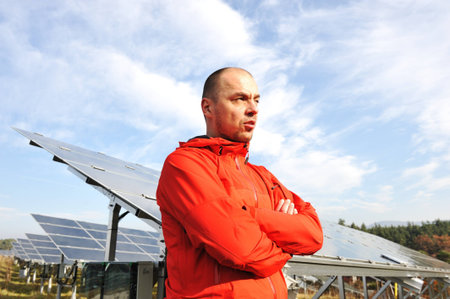 Young male engineer with solar panels in background