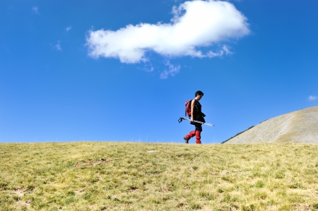 Hiker in mountains at grassland with sky aboveの写真素材