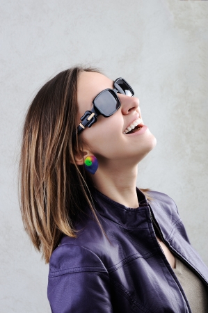 A pretty girl smiling in a  sunglasses on grey backgroundの写真素材