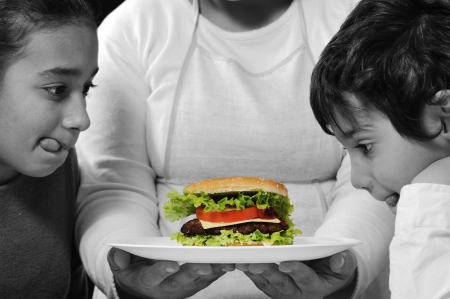 Mother giving a burger to son and daughterの写真素材