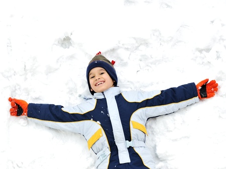 Happy child lies on snow groundの写真素材