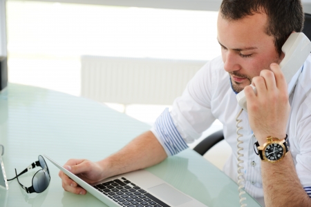 Young business man sitting and resting at modern office making a callの写真素材