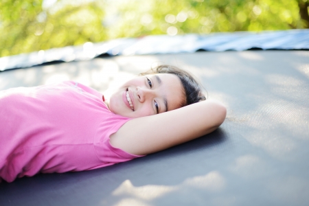 Portrait of a smiling little girl lying on green grassの写真素材