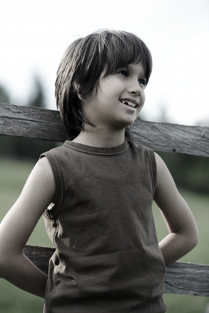 Kid standing on fence outdoorsの写真素材