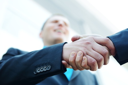 Business shaking hands in front of modern building with copy space (selective focus)の写真素材