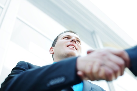Business shaking hands in front of modern building with copy space (selective focus)の写真素材
