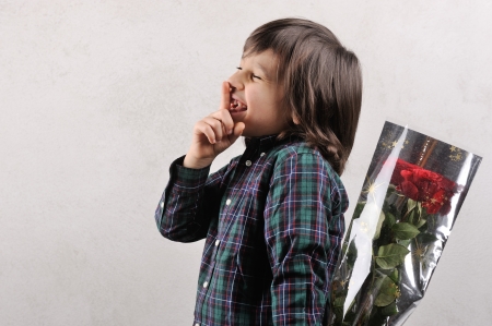 Handsome little boy with a rose as a gift in his handの写真素材