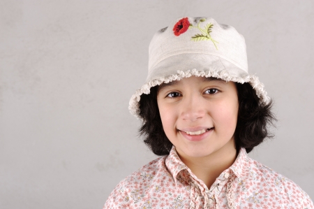 Smiling girl showing teeth wearing a  hat with red flowerの写真素材