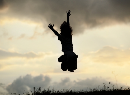 Active little boy jumping and having happy time on summer meadow by sunsetの写真素材