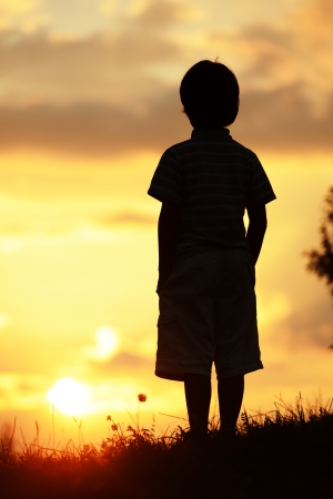 Active kid spending time on summer meadow by sunsetの写真素材