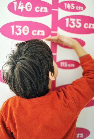 Boy growing tall and measuring his height on the wall