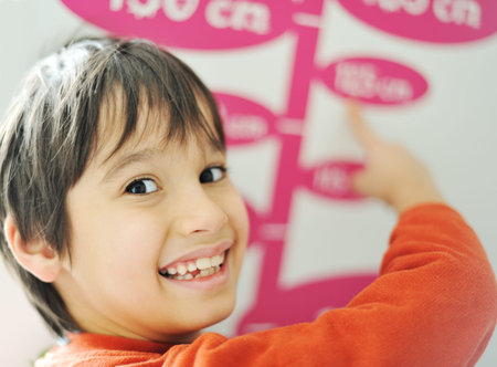 Boy growing tall and measuring his height on the wallの写真素材