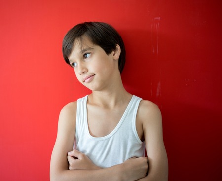 Adorable little happy boy looking at camera on red の写真素材