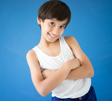 Adorable little happy boy looking at camera on blue wallの写真素材