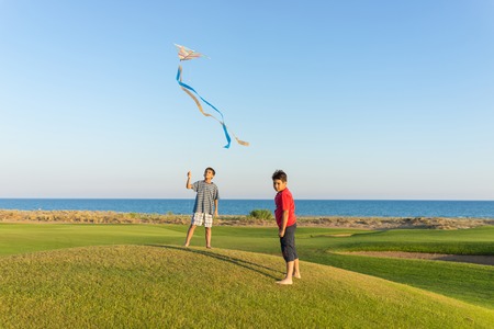Running with kite on summer holiday vacation, perfect meadow and sky on seasideの写真素材