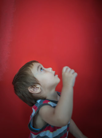 Cute little boy in front of red wall