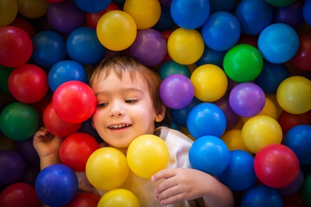 Happy cute child playing and having fun at kindergarten with colorful ballsの写真素材