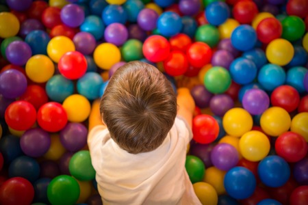 Happy cute child playing and having fun at kindergarten with colorful ballsの写真素材