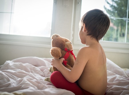 A little cute boy with Teddy bear on the bedの写真素材