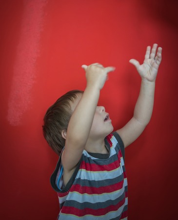 Cute little boy in front of red wallの写真素材