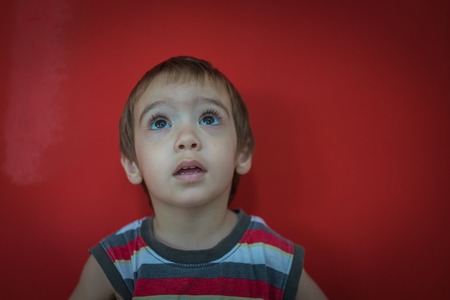 Cute little boy in front of red wallの写真素材