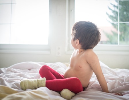 A little cute child with Teddy bear on the bedの写真素材