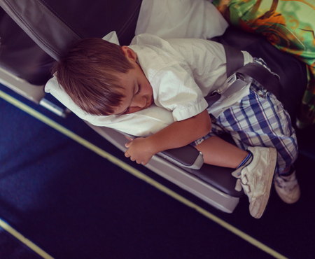 Kid sleeping inside the airplane during the flightの写真素材