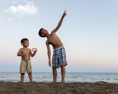Little boys on the beach heaving funの写真素材