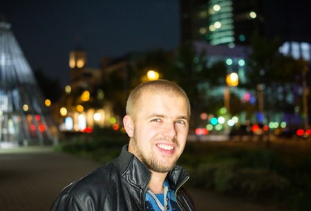 Handsome young hipster outside in the night cityの写真素材